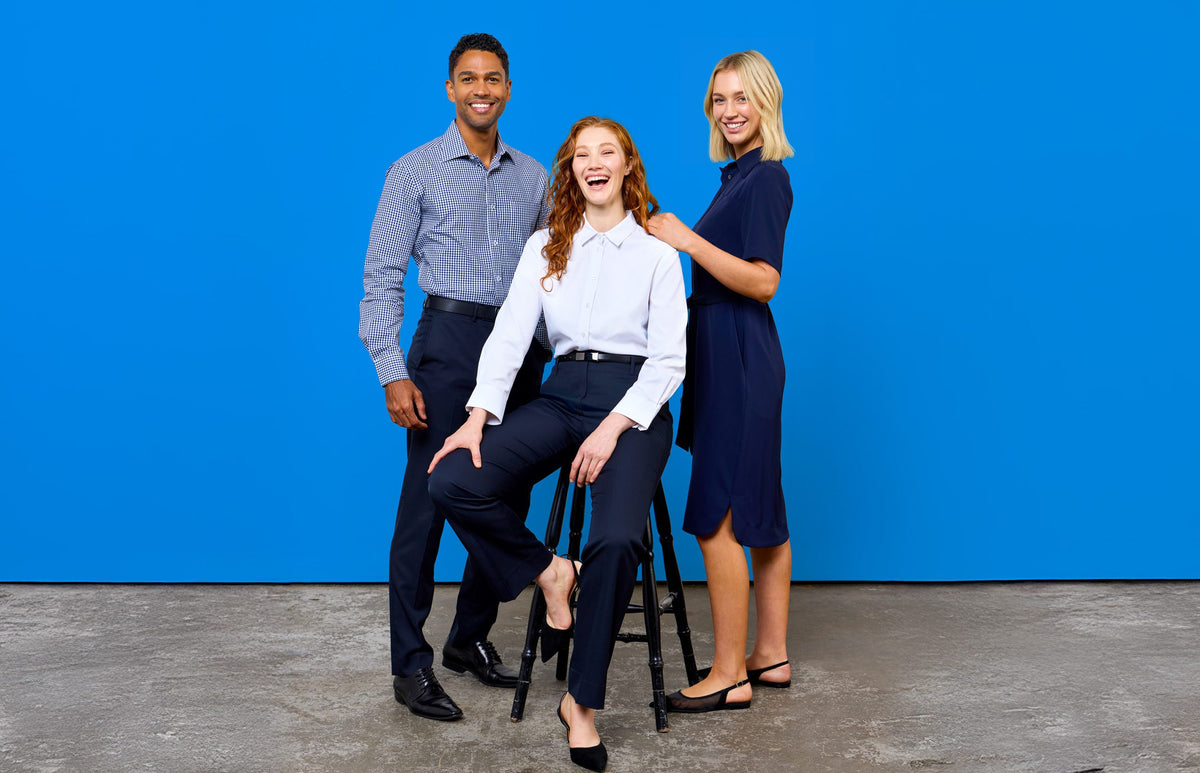 A polished team in modern corporate uniform, featuring navy tones, tailored fits, and effortless style against a bold blue backdrop.