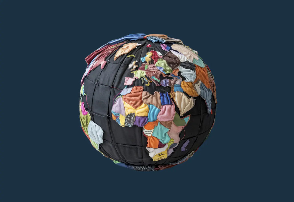 A globe made from colourful fabric scraps stitched together, symbolising global collaboration, ethical manufacturing, and sustainable textile practices in the uniform industry.