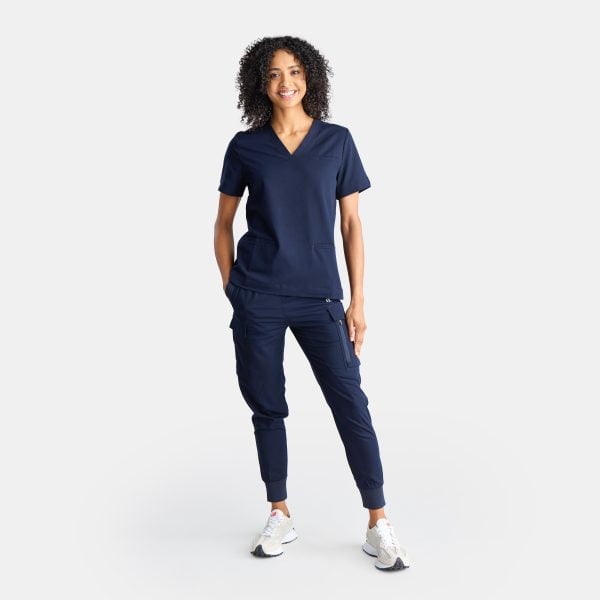 Full Body View of a Woman Wearing the Designs to You Twilight Scrubs. the Vibrant Navy Colour Adds a Pop of Freshness to the Uniform, While the Comfortable Fit Ensures Ease of Movement Throughout the Day. the Image Highlights the Stylish Design and High-quality Construction of the Scrubs, Making Them a Great Choice for Healthcare Professionals.