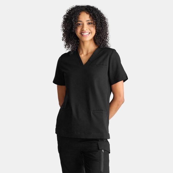 a Model with Olive Skin and Curly Hair Wearing Black Designs to You Scrubs is Captured in a Joyful Smile. the Model Radiates Confidence and Positivity While Showcasing the Stylish Black Scrubs. the Black Scrubs Provide a Sleek and Professional Appearance, Complementing Her Overall Look. the Model's Smile Reflects the Comfort and Satisfaction That Comes with Wearing Designs to You Scrubs.