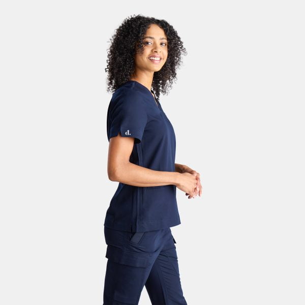 Side View of a Woman Wearing the Designs to You Twilight Scrubs. the Vibrant Navy Colour Adds a Pop of Freshness to the Uniform, While the Comfortable Fit Ensures Ease of Movement Throughout the Day. the Image Highlights the Stylish Design and High-quality Construction of the Scrubs, Making Them a Great Choice for Healthcare Professionals.
