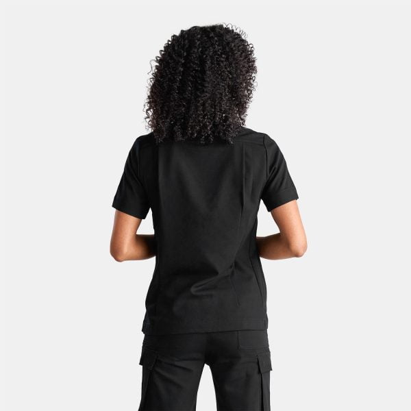 Back View of a Woman Wearing the Designs to You Midnight Black Scrubs. the Sleek Black Color Adds a Touch of Elegance to the Uniform, While the Comfortable Fit Allows for Ease of Movement. the Image Showcases the Modern Design and Attention to Detail of the Scrubs, Making Them a Perfect Choice for Healthcare Professionals Seeking Both Style and Functionality.