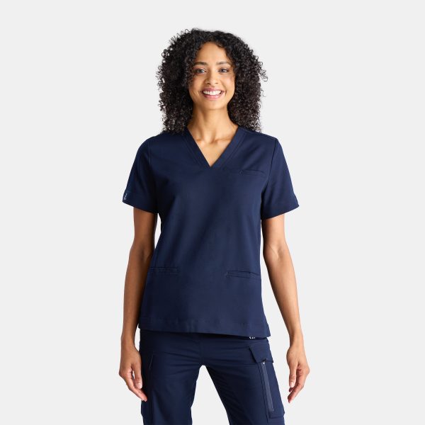 a Woman Wearing the Designs to You Twilight Scrubs. the Vibrant Navy Colour Adds a Pop of Freshness to the Uniform, While the Comfortable Fit Ensures Ease of Movement Throughout the Day. the Image Highlights the Stylish Design and High-quality Construction of the Scrubs, Making Them a Great Choice for Healthcare Professionals.