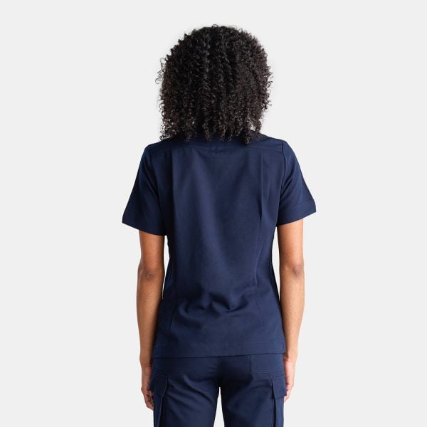 Back View of a Woman Wearing the Designs to You Twilight Scrubs. the Vibrant Navy Colour Adds a Pop of Freshness to the Uniform, While the Comfortable Fit Ensures Ease of Movement Throughout the Day. the Image Highlights the Stylish Design and High-quality Construction of the Scrubs, Making Them a Great Choice for Healthcare Professionals.
