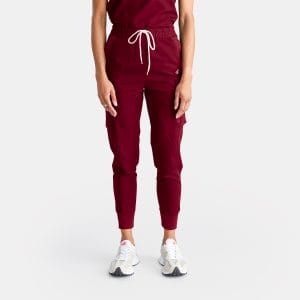 Unisex Cargo Jogger Scrub Pant — Sangria/Red — Designs To You 3 | Designs To You Photo Showcasing Our Cargo Pants' Pockets on a Female Healthcare Professional Confidently Wearing Vibrant Sangria Red Cargo Jogger Scrub Pant