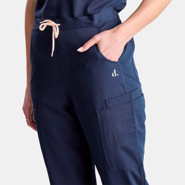 a Woman Wearing Our Best-selling Modern Twilight Navy Pants. These Straight Leg Style Pants Are Popular Among Our Customers and Feature Five Deep Pockets, Providing Convenient Storage for Nurses on the Go.