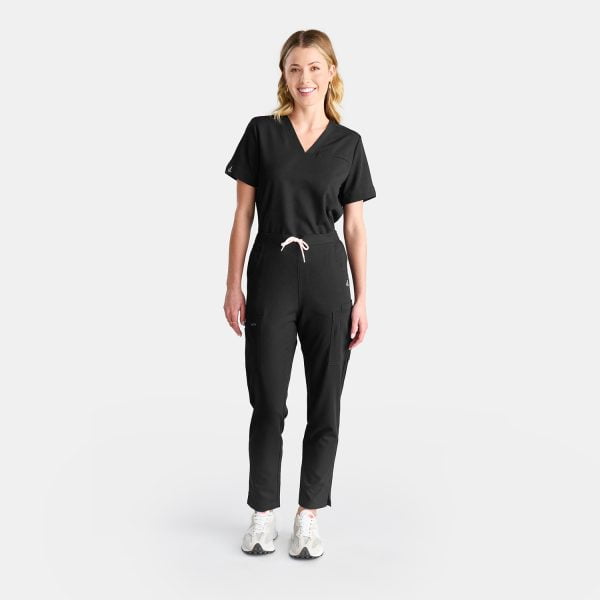 Full Body View of a Woman Wearing Designs to You Midnight Black Modern Scrub Pants and Our Modern Scrub Top. the Pants Feature a Stylish Straight Leg Design and Five Deep Pockets, Combining Functionality with a Sleek Aesthetic