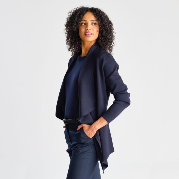 Side View of a Woman in a French Navy Milano Knit Waterfall Cardigan, Paired with Matching Trousers and a Belt.