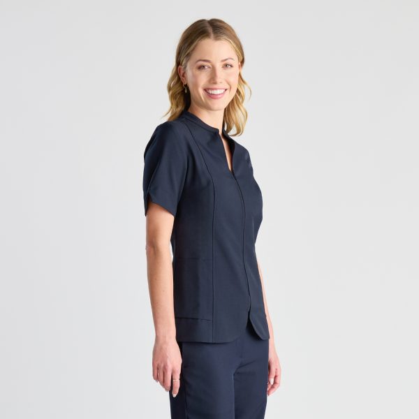 a Woman Smiles Slightly, Wearing a Sleek French Navy Pharmacy Tunic with a Zipper Front and Structured Panels for a Professional Fit.