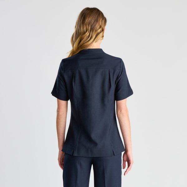 the Back View of a French Navy Zip Front Pharmacy Tunic on a Woman, Showcasing the Tunic's Form-fitting Style and Back Details.