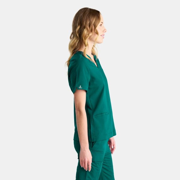 Side View Woman Wearing the Designs to You Fern Green Scrubs. the Sleek Green Colour Adds a Touch of Elegance to the Uniform, While the Comfortable Fit Allows for Ease of Movement. the Image Showcases the Modern Design and Attention to Detail of the Scrubs, Making Them a Perfect Choice for Healthcare Professionals Seeking Both Style and Functionality.