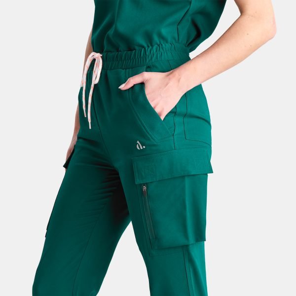 the Image Depicts a Woman Wearing Our Stylish Cargo Jogger Scrub Pants in a Lovely Modern Fern Green Colour. These Pants Feature Six Pockets, Offering Ample Storage Space for Healthcare Professionals. the Image Showcases the Modern Design and Vibrant Colour of the Pants, Making Them a Fashionable and Functional Choice for Medical Professionals.