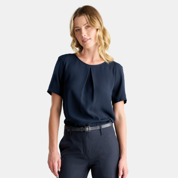 a Woman is Standing Posing for the Camera, Wearing a Short-sleeved Navy Blouse. the Blouse Features a Subtle Pleat at the Front, Giving It a Touch of Elegance. the Sleeves Are Cuffed for a Smart Finish. She is Paired with Matching Navy Trousers That Are Fitted with a Black Belt to Cinch at the Waist. the Outfit Suggests a Professional, Business-casual Look.