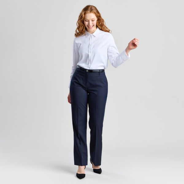 Full-length Portrait of a Smiling Model Wearing the Relaxed Leg Pant in French Navy, Captured Mid-stride. the Image Conveys Motion and a Light-hearted Feel, Paired with a Soft White Blouse and Black Pumps.
