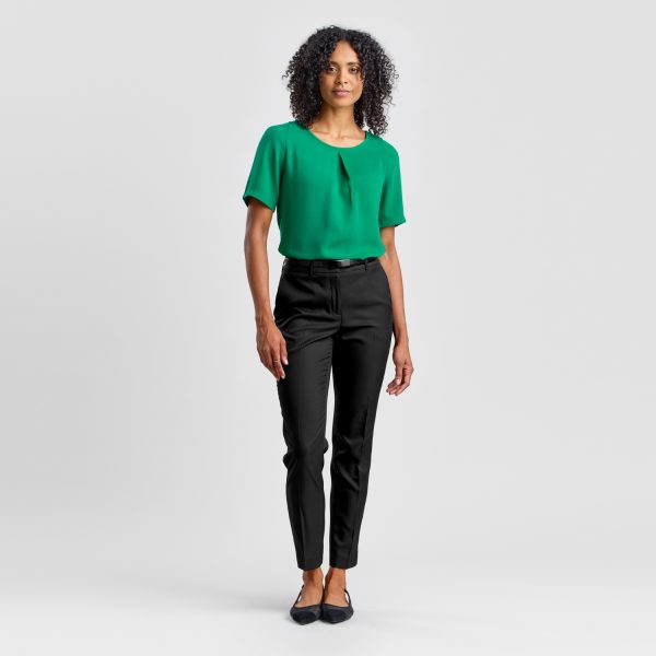 Front View of a Woman Wearing Black Cropped Slim Leg Pants Paired with a Green Blouse and Black Flats.