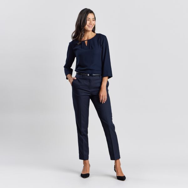 Full Body View of a Smiling Woman in French Navy Cropped Slim Leg Pants and Matching Navy Blouse with Black Heels, Hands on Hip.
