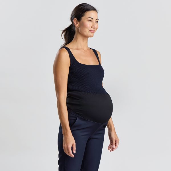 Angled View of a Relaxed Leg Maternity Pant in Navy with a Pregnant Woman Smiling Slightly, Showcasing the Side and Front Fit of the Navy Maternity Pants Paired with a Dark Sleeveless Top.