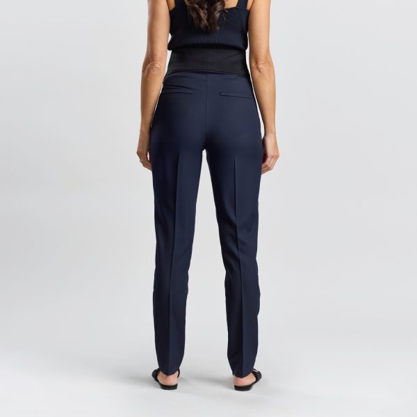 Back View of a Relaxed Leg Maternity Pant in Navy Displaying the Rear Design and Fit of the Pants on a Woman with Her Back Turned, Featuring a High-rise Back Panel and Welt Pockets.