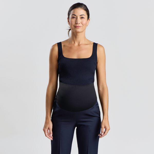 Front View of a Relaxed Leg Maternity Pant in Navy Featuring a Woman Standing Straight, Wearing a Dark Navy, Sleeveless Top and Relaxed-fit Navy Maternity Pants with a Belly Panel.