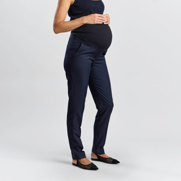 Side Profile of a Relaxed Leg Maternity Pant in Navy Showing a Pregnant Woman Cradling Her Belly, Highlighting the Side Stretch Panel and the Drape of the Navy Pants.