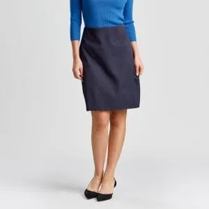 a Woman Viewed from the Front, Hands Slightly Touching the Pockets of Her Navy A-line Skirt, Complemented by a Bright Marine Blue Top and Black Flats, Exemplifying a Professional and Polished Look.