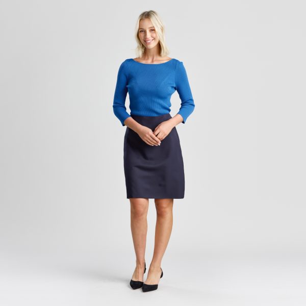 Full-length Photo of a Woman Smiling Confidently, Dressed in a Navy A-line Skirt with Pockets and a Snug Marine Blue Top, Completed with Black Heels.