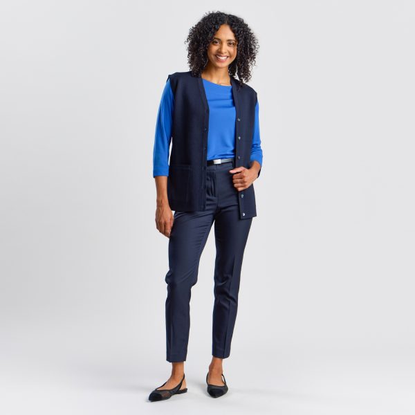 Full-length Image of a Woman Smiling in a Women's Milano Knit Button Front Vest in French Navy, Styled with a Boat Neck Top and Chino Pants for a Smart and Coordinated Workwear Ensemble.