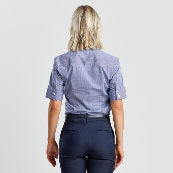 Rear View of a Woman with Blonde Hair Wearing a Navy Mini Check Short Sleeve Shirt, Showing the Button Detail on the Rolled-up Sleeves and the Tailored Fit Against a White Background.
