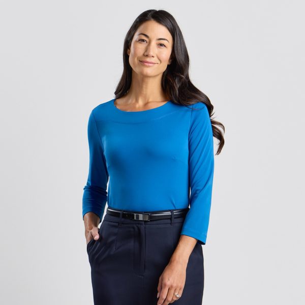 a Woman Facing the Camera with a Slight Smile, Wearing a Marine Blue Soft Knit 3/4 Sleeve Boat Neck Top and Navy Skirt, on a White Background.