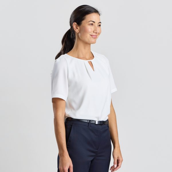 a Model is Angled to the Side, Showcasing a Short-sleeved Ivory Keyhole Blouse, Paired with Navy Trousers.