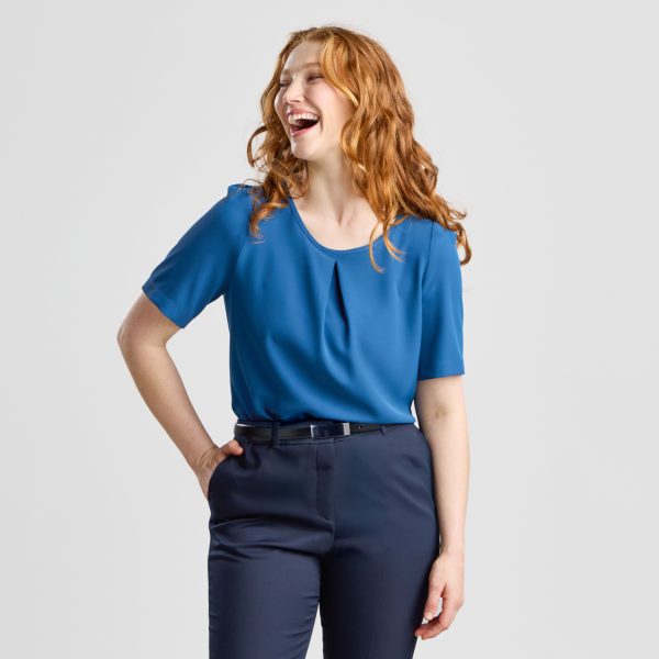 Woman Laughing While Wearing a Blue Centre Pleat Blouse Paired with Navy Trousers and a Belt.