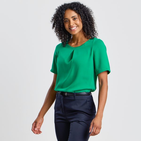 a Smiling Model at a 45-degree Angle Highlights the Fit of an Emerald Green Blouse Paired with Navy Trousers.