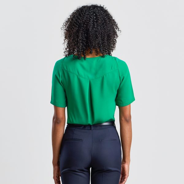 Back View of an Emerald Green Blouse on a Model, Showing the Pleat Detail and Fit with Navy Trousers.