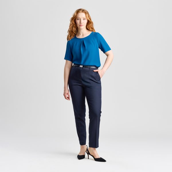 Full-body View of a Woman in a Blue Centre Pleat Blouse and Navy Trousers, with One Hand in Her Pocket and Wearing Black Heels.