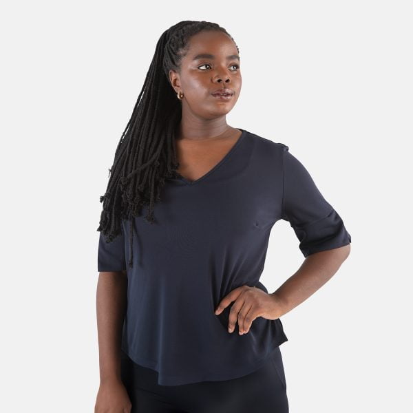 a Woman Wearing a Navy Short Sleeve V-neck Top in Soft Knit. the Women's Blue Work Shirt is Comfortable and Flattering.