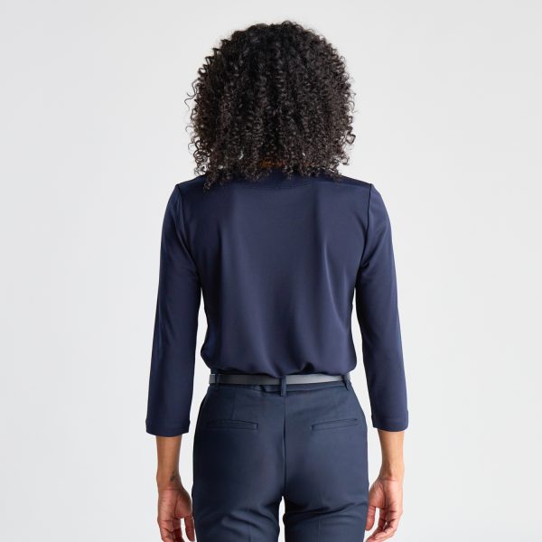 Rear View of a Woman with Curly Hair Wearing a Navy Soft Knit 3/4 Sleeve Boat Neck Top and Matching Pants, Standing Against a White Backdrop.