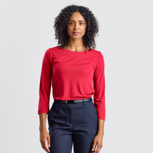 Woman Facing Forward Wearing a Ruby Soft Knit Boat Neck Top, with a Subtle, Thoughtful Expression.