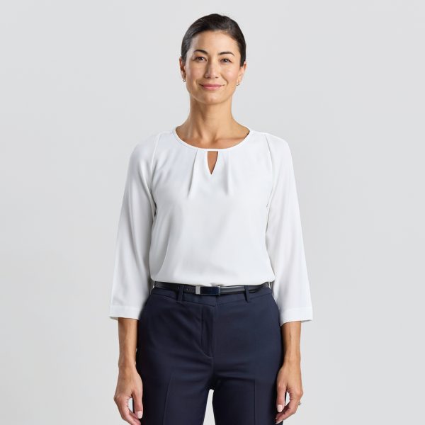 a Model Standing Confidently in an Ivory Keyhole Blouse, Paired with Navy Trousers.