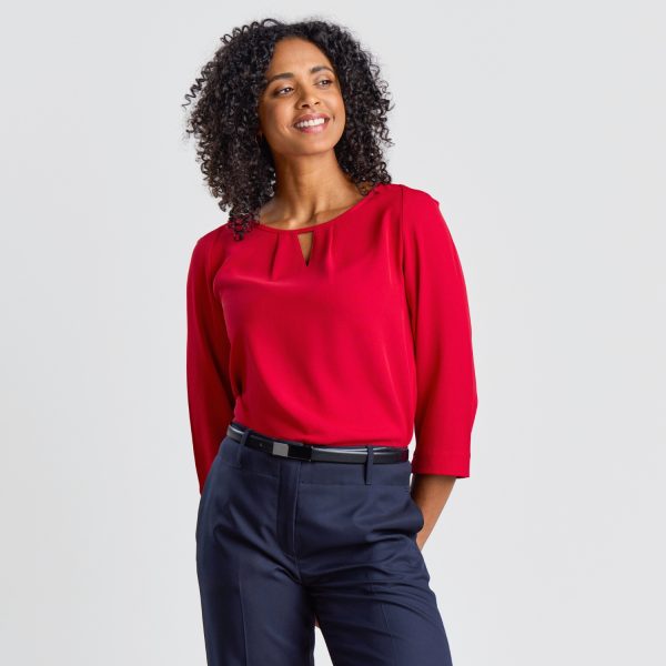 a Model Angled at 45 Degrees Wearing a Ruby Blouse with Keyhole Detail, Against a Neutral Setting.