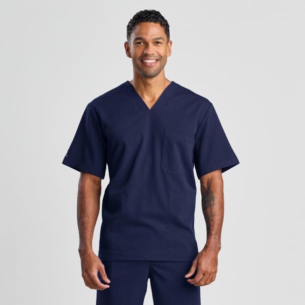 Front View of a Man Smiling and Confidently Modeling the Men's Modern Scrub Top in Navy, Showcasing a V-neck and Chest Pocket Design.