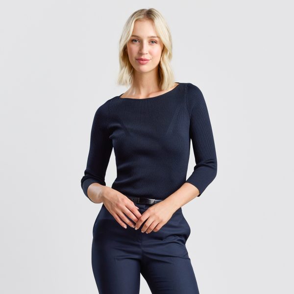 a Woman in a Women's Rib Knit Boat Neck Top in French Navy, with a Slim Fit and Ribbed Texture, Paired with Matching Navy Chino Pants and Classic Black Ballet Flats.
