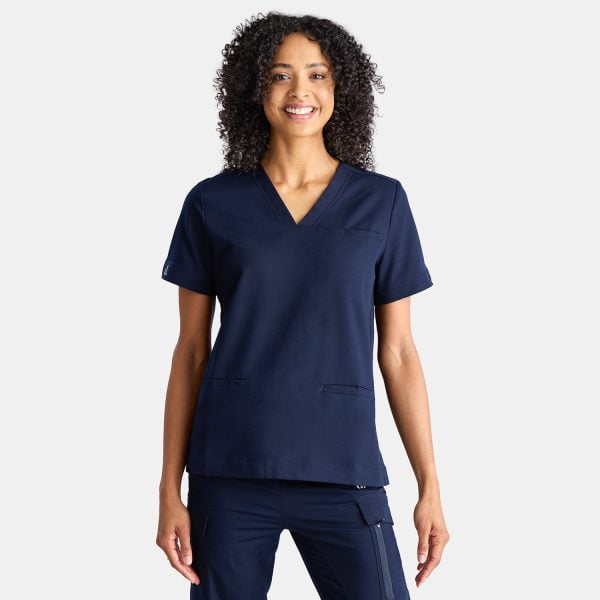 a Model with Olive Skin and Curly Hair Wearing Navy Designs to You Scrubs is Captured in a Joyful Smile. the Model Radiates Confidence and Positivity While Showcasing the Stylish Navy Scrubs. the Navy Scrubs Provide a Sleek and Professional Appearance, Complementing Her Overall Look. the Model's Smile Reflects the Comfort and Satisfaction That Comes with Wearing Designs to You Scrubs.