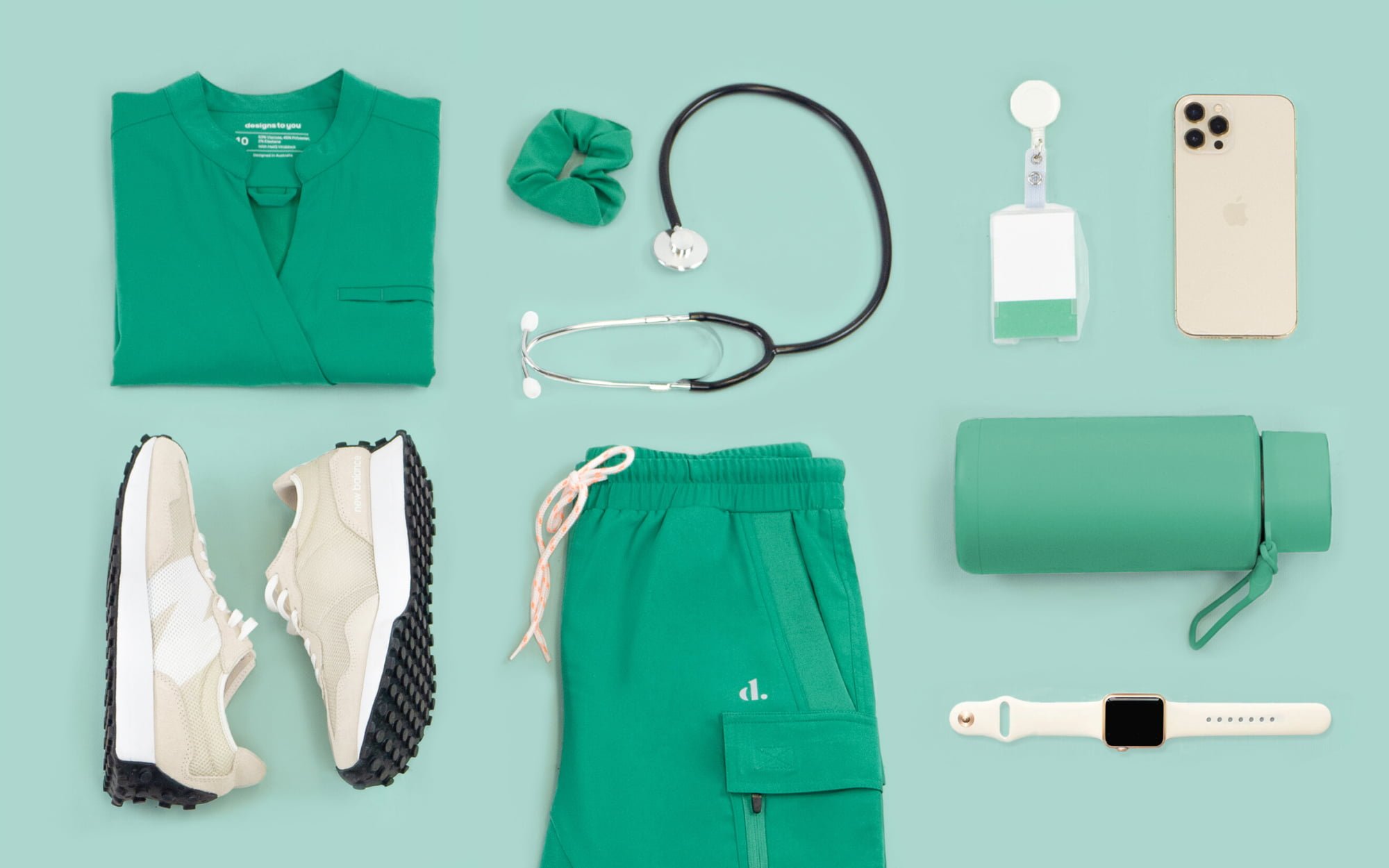 The banner for the article 'The Anatomy of the Perfect Scrubs' features a flat lay of green coloured nursing scrubs, beige sneakers and an assortment of accessories that a healthcare worker may carry with them at work. The items lay atop a mint green background.