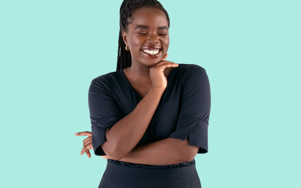 The banner for the article 'Made For You-niforms' depicts a smiling female model standing in front of an aqua coloured background. She is wearing a professional, well-fitted and stylish black v-neck blouse.