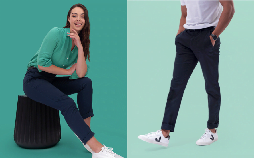 The banner for the article 'Giving New Life to Your Old Uniforms' features a split image of two models wearing stylish, modern and professional uniforms. The female model is wearing a green linen blouse with navy slacks and white sneakers. She is sitting on a black chair in front of a teal coloured background. The male model is wearing navy slacks, a white cotton t-shirt and white Veja sneakers. He is walking in front of a mint coloured background, and is only visible from the neck down. The images green colour palette reflects the topic of the blog - sustainable uniforms.