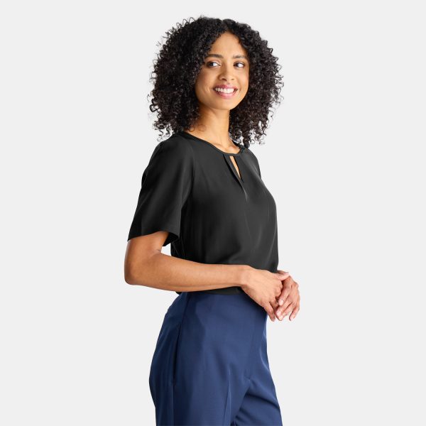 a Woman Wearing a Tucked in Black Work Shirt with Navy Straight Leg Pants. the Sale Short Sleeve Top is Work Uniform. the Keyhole Blouse is Comfortable and Stylish, Designed by Designs to You.