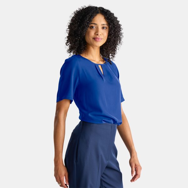 a Stylish Woman in a Professional Short Sleeve Blue Top. the Keyhole Blouse is Comfortable and Modern, Paired with a Pair of Navy Work Pants