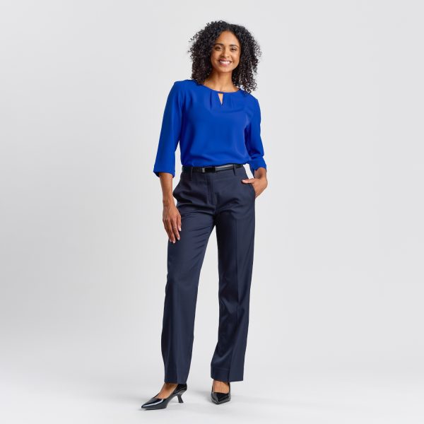 Full-length Image of a Woman Standing Confidently in a Royal Blue Keyhole Blouse Paired with Navy Trousers and Black Heels.