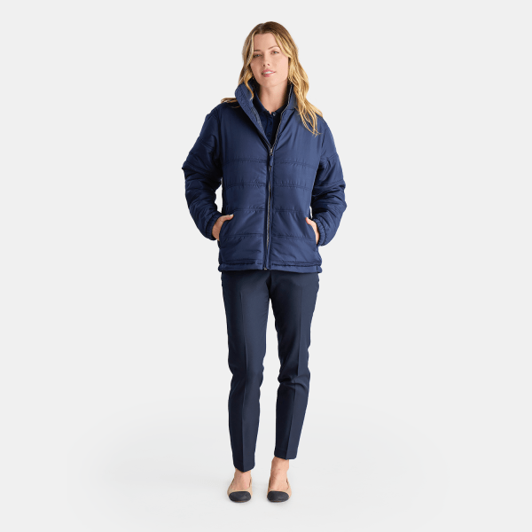 Casual Yet Professional, a Woman Wears a Structured Navy Blue Puffer Jacket and Slim-fit Pants, Completed with Subtle Black Flats, Suitable for a Practical Work Uniform.