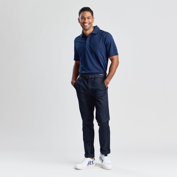 Full-body Portrait of a Smiling Man Wearing Men's Slim Style Chino Pant in French Navy with a Coordinated Polo Shirt and Sporty White Sneakers, Projecting a Relaxed Yet Professional Style.